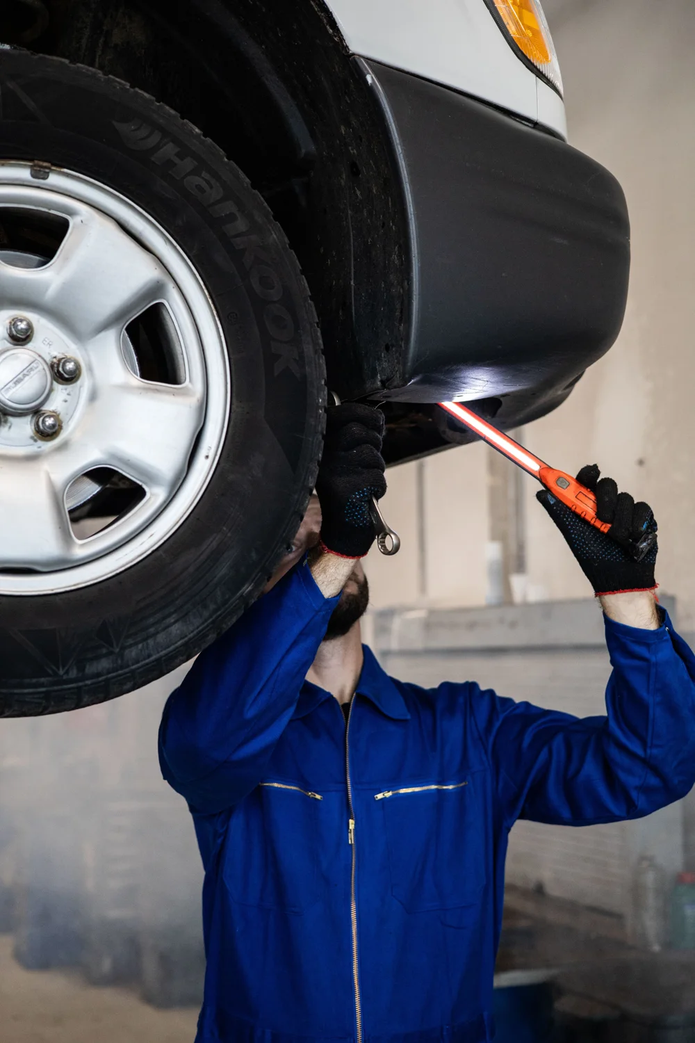 Technician checking under a vehicle with an inspection lamp